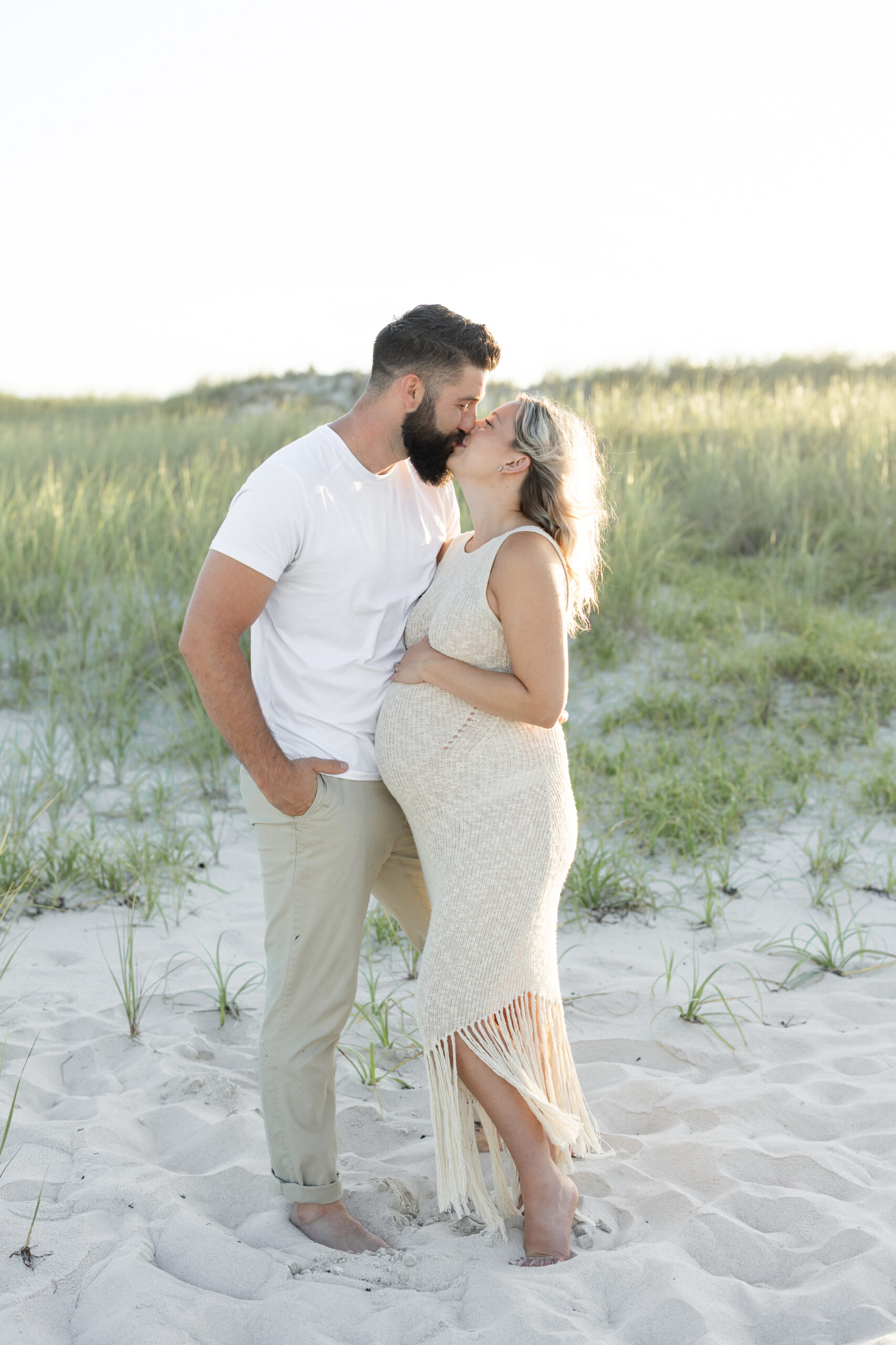 An image of a pregnant mama and her husband sharing a kiss during her maternity session on Island Beach State Park. She was photographed by Natalie Beach Photography, a South Jersey Family Photographer.