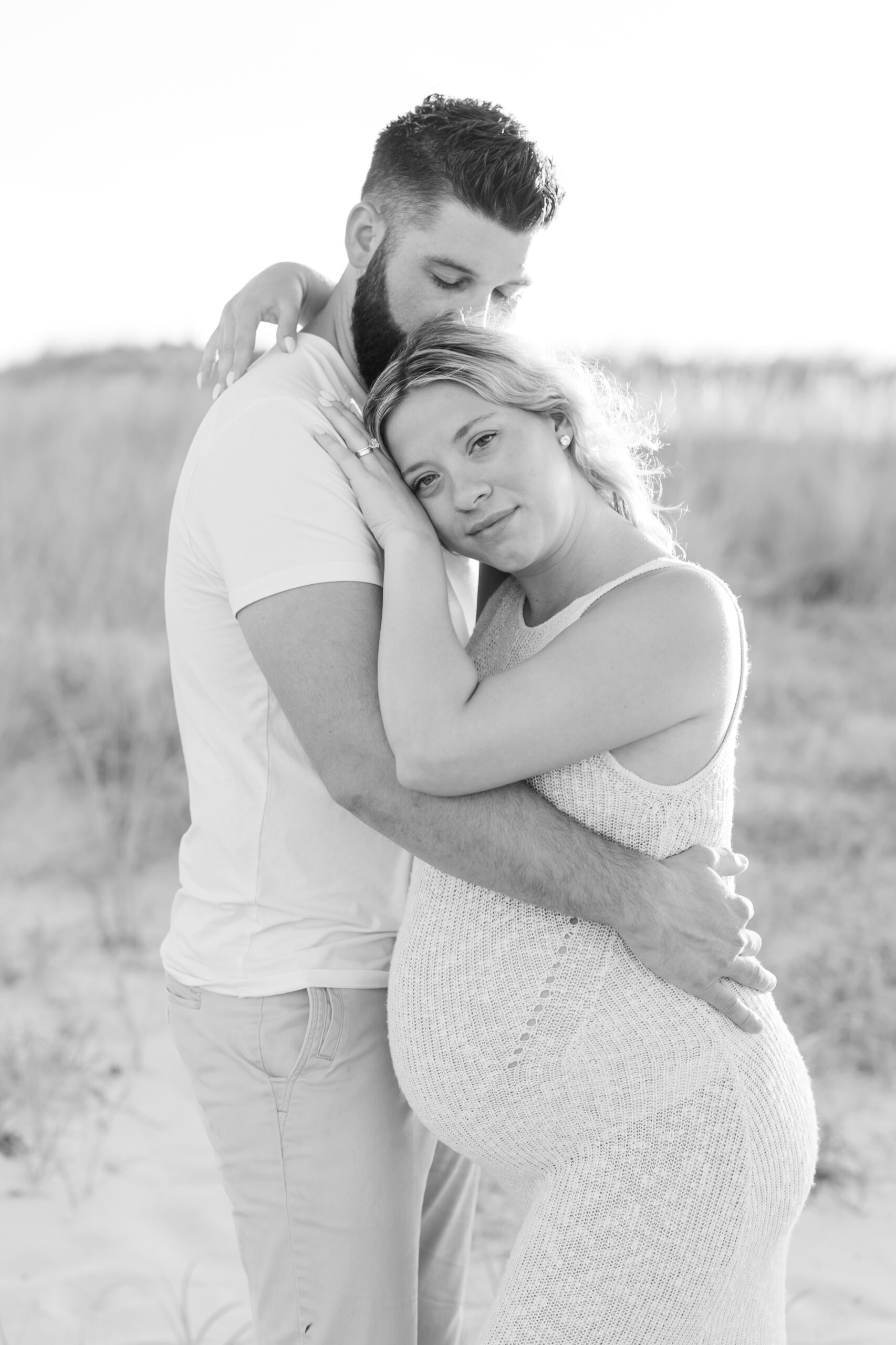 An image of a pregnant mama and her husband during their maternity session on Island Beach State Park. This image is in black and white. They were photographed by Natalie Beach Photography, a South Jersey Family Photographer.